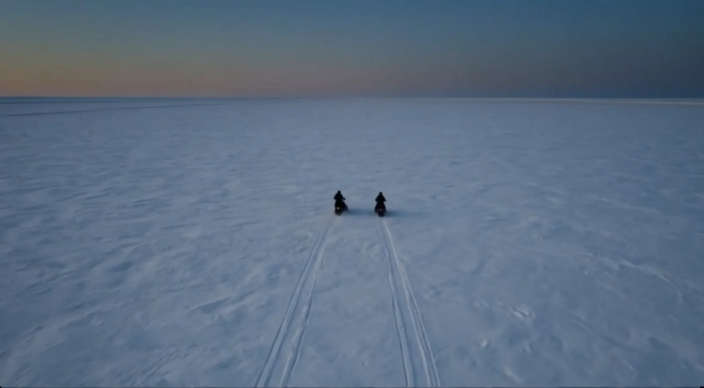 A lone figure looking across an icy blue landscape beneath a vast planet